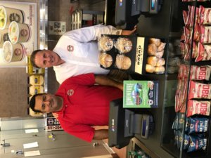 Franchisee Manuel Pizaño-Carlo poses with President and CEO Eric Wolfe behind the register at the newly opened 100th Erbert & Gerbert’s location.